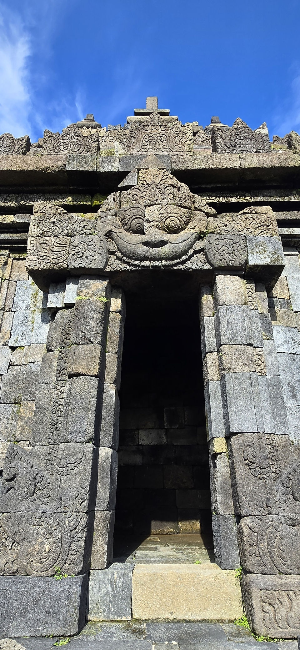 Ancient stone temple entrance with intricate carvings under a clear blue sky, creating a sense of mystery and historical grandeur.