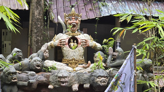 A statue of a mythical creature with gold details, open chest revealing figurines. Surrounded by monkey statues; leafy background.