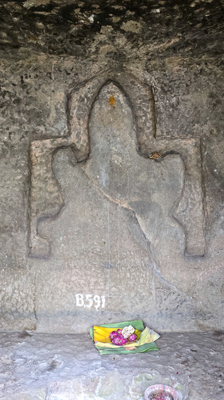 Stone shrine inside a cave with offerings on a rock longga altar. Mossy walls, scattered leaves, and earthy tones create a serene atmosphere.