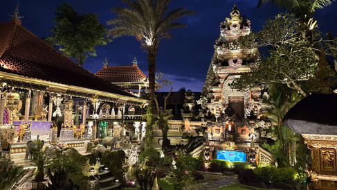 Beautiful temple illuminated at night, surrounded by statues and manicured gardens