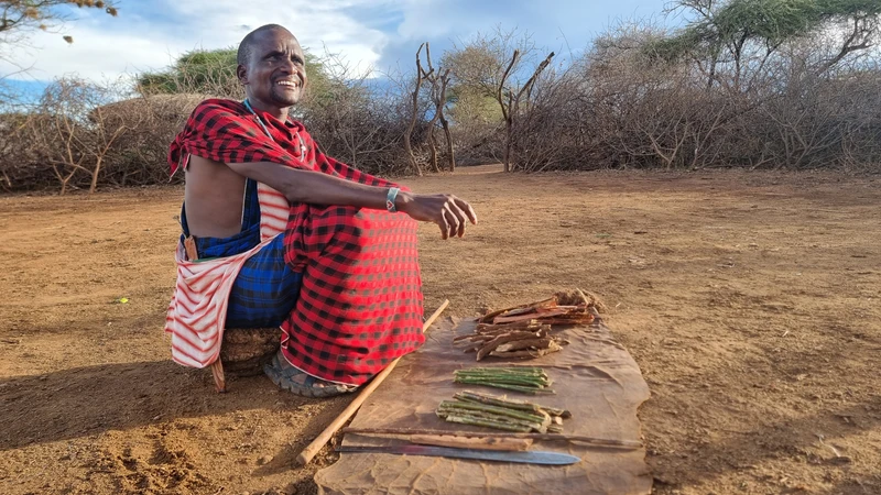 Community mentor preparing traditional food outdoors in Kenya.