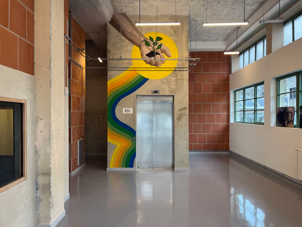 Mural on interior concrete wall showing hand with seed and rainbow designed by ATMA - Paris interior mural art