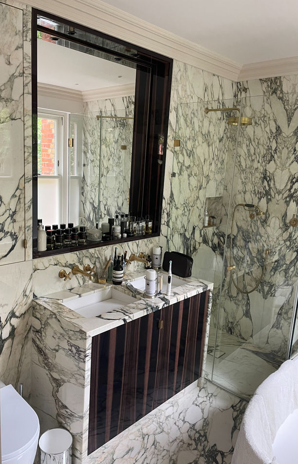 ELEGANT VANITY UNIT AND BESPOKE MIRROR IN EBONY MACASSAR Beautiful Italian marble surrounds this bespoke vanity unit in ebony Macassar with matching heated mirror. This bathroom is pure luxury. Creating the inset mirror to was an exercise in careful woodgrain matching. It also has gorgeous tailor-made details such as an opening for tissues and carefully placed lighting above