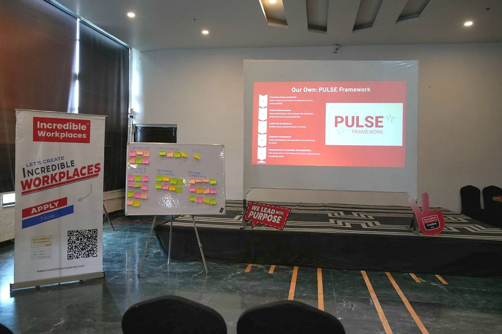 Conference room with a "Pulse Framework" presentation projected on the wall, a board covered in sticky notes, and an "Incredible Workplaces" banner.