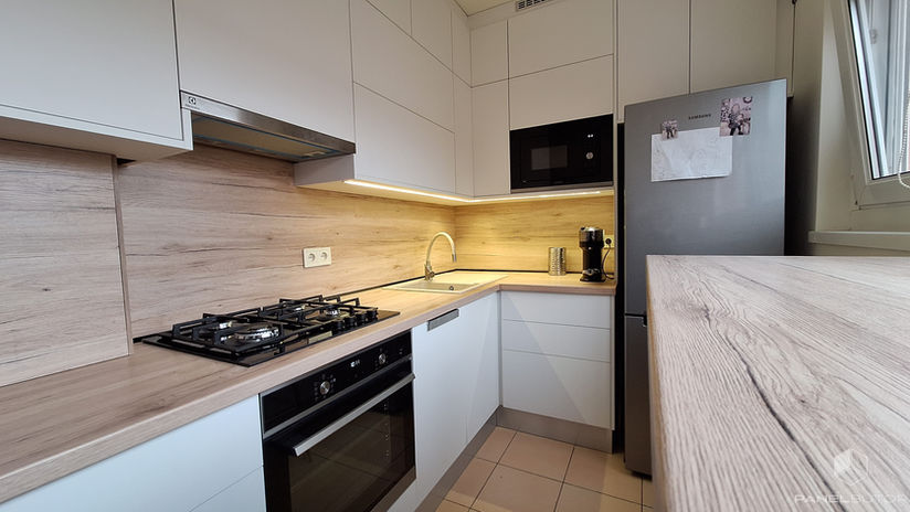 Modern konyha valós fotó fehér frontokkal és fa munkapulttal fa falburkolattal