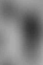 a black and white photo of a bride and groom walking away from the camera down a corridor together while holding hands.