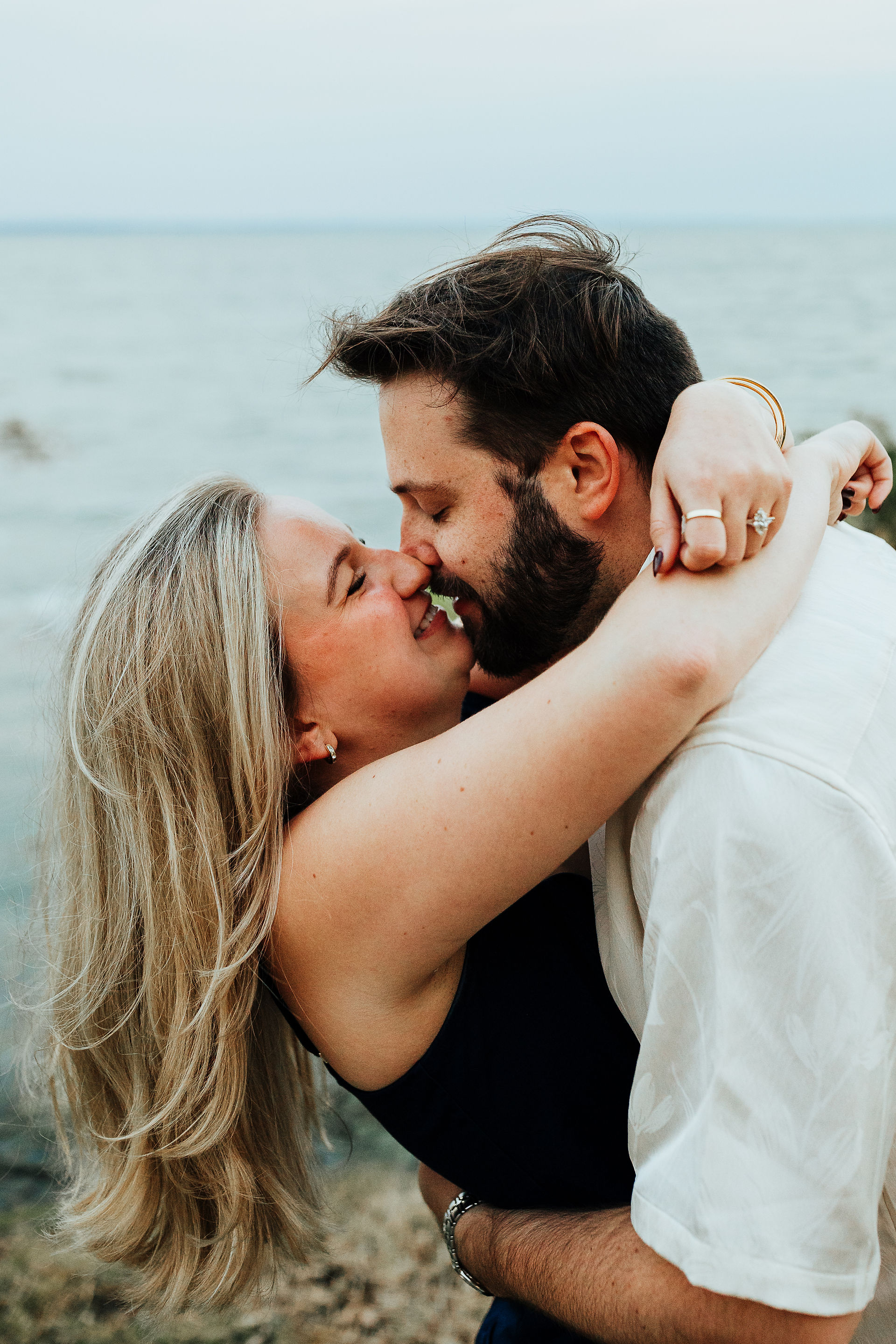 a man and woman embrace while the man leans the woman back while they both smile, almost kissing