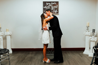 a bride and groom embrace and share a kiss at the wedding podium in the Orange County Courthouse wedding chapel.
