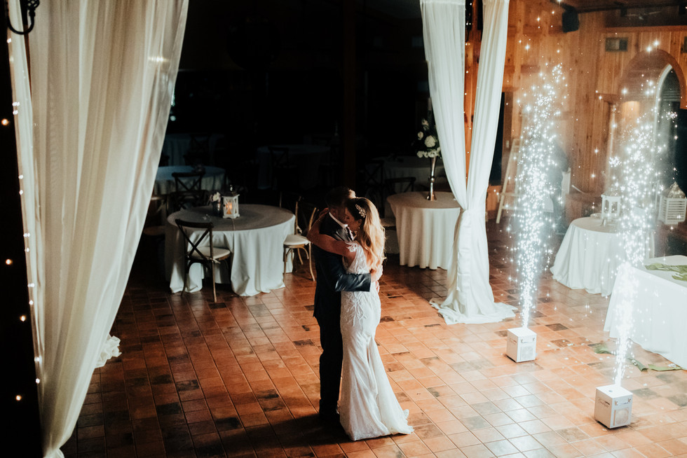 Bride and groom dance together with sparkler machines behind them