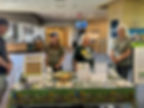 Bird conservation booth in a lobby, with four people talking around a table covered in bird photos, flyers, and signs.