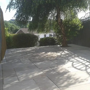 Natural stone slabs in back garden with tree.webp