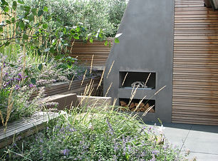 Outdoor concrete fireplace in garden, with nauralistic planting and wooden screening