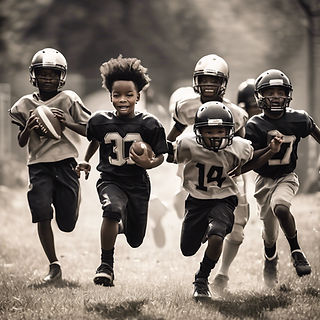 a group of black kids in football gear running after a kid with a football in his hands.jp