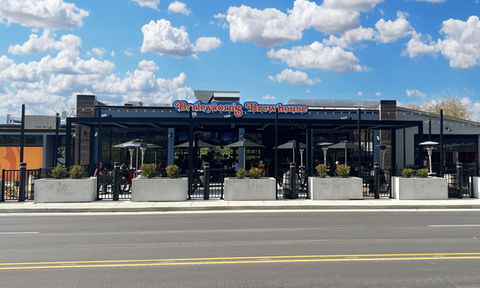 Exterior view of Barleycorn’s Brewhouse in Wilder, Kentucky, showing the historic firehouse and covered patio area with guests enjoying food and drinks.