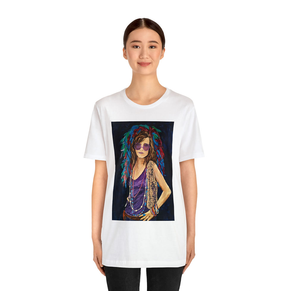 Thumbnail: A white short sleeve t-shirt featuring a colorful portrait of Janis Joplin. The artwork shows her with vibrant, multicolored hair, wearing purple-tinted sunglasses and a stylish outfit. The model wearing the t-shirt is standing casually, with one hand in their pocket and a plant in the background. The product is titled 'Janice Joplin Short Sleeve T-Shirt.