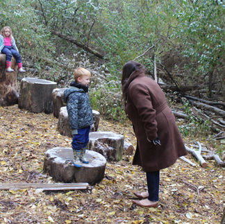 adult speaking to child standing on stump