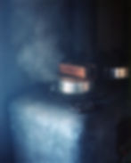 Steam rising from a metal pot with a copper lid in a dim room