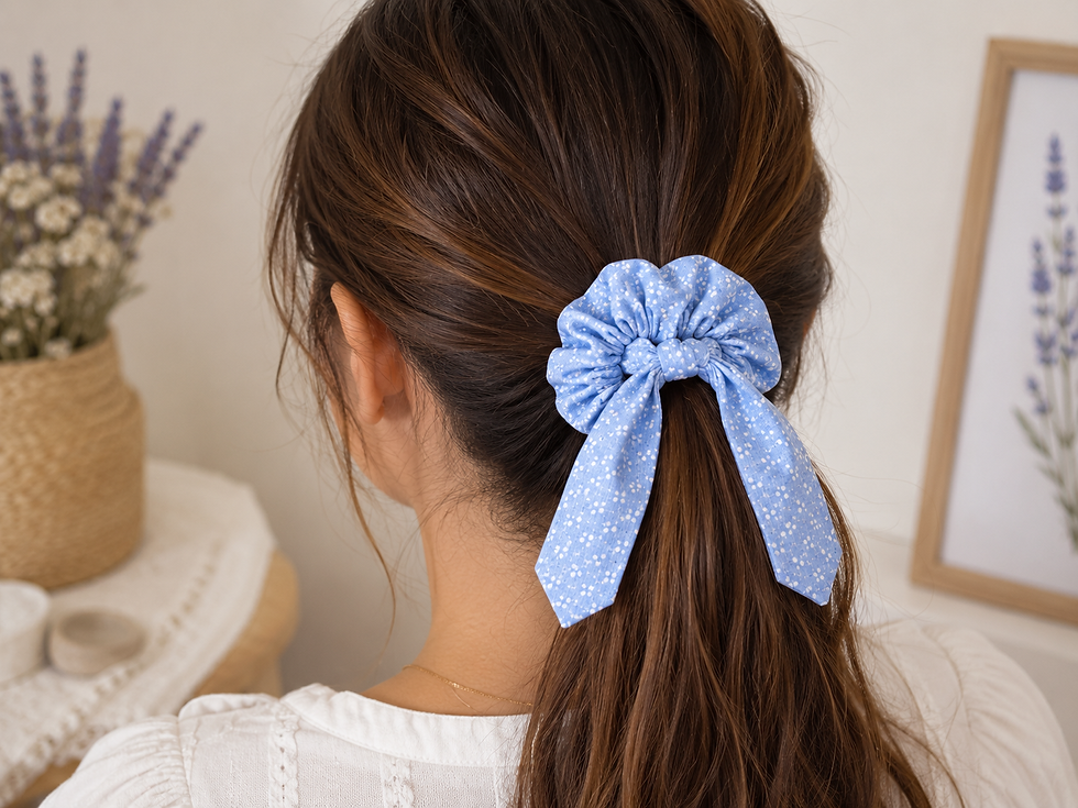Thumbnail: Chouchou en coton bleu ciel à petits motifs blancs avec rubans amovibles porté en queue de cheval.