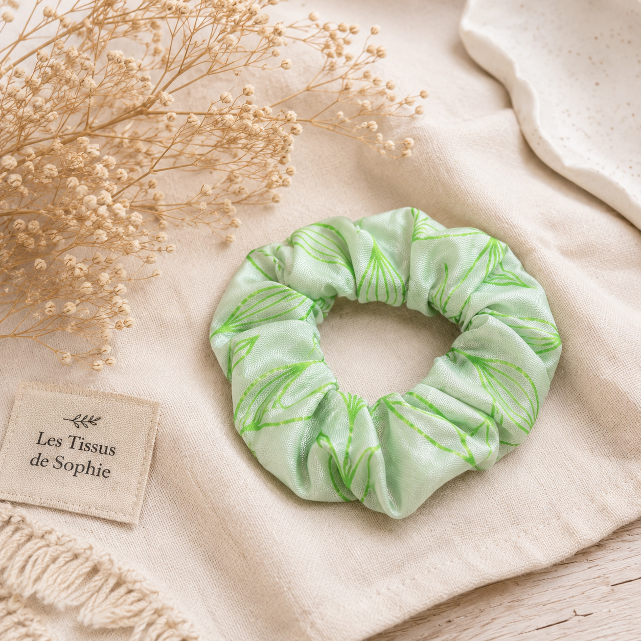 Chouchou fantaisie vert à motifs feuillage sur une mise en scène naturelle avec fleurs séchées