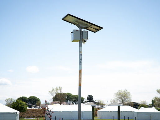 Solar powered security camera tower in middle of pop up tents