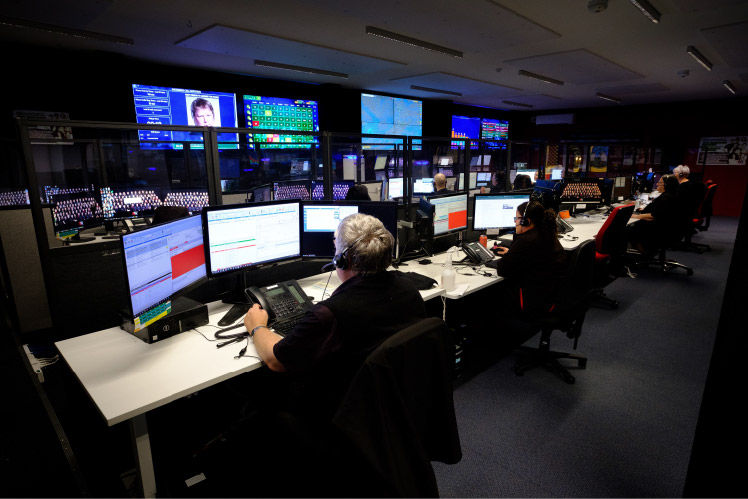 Afterhours camera monitoring staff working in front of wall of screens