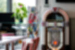 Authentic Wurlitzer jukebox at Jukebox Diner Hamilton, surrounded by vintage car magazines and glowing Coca-Cola signage - premier 1950s Americana exhibit