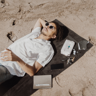 Urbane Hemp Box TLCBD Pouch and Urbane Hemp Mask on the beach with man on towel