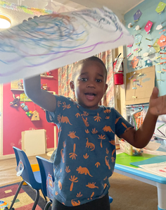 Happy boy raising his arms in celebration after finishing a letter learning activity.