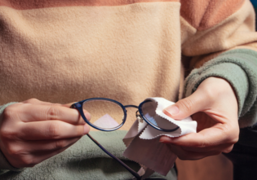 An image of someone cleaning their glasses with a microfiber cloth.