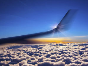Airplane wing in sunset over sea of fog