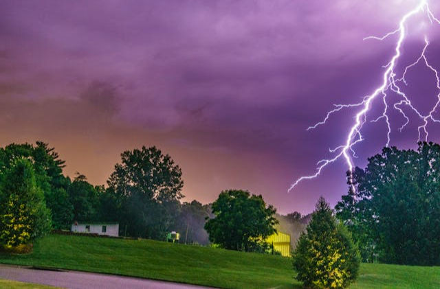 Lightening in purple sky on green nature