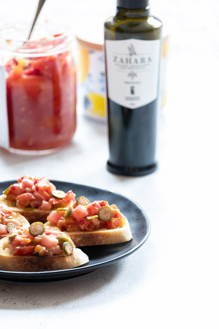 Crostini on a black plate with a bottle of olive oil on the background
