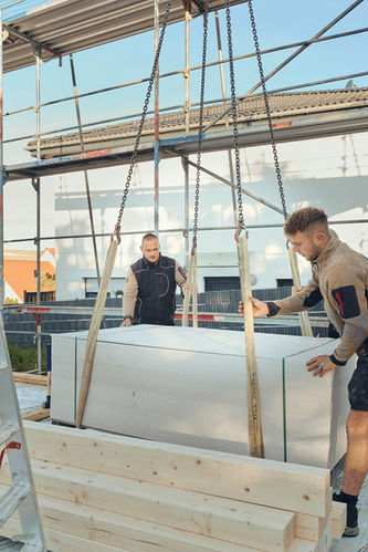 Zwei Bauarbeiter nehmen eine Ladung Holzplatten entgegen