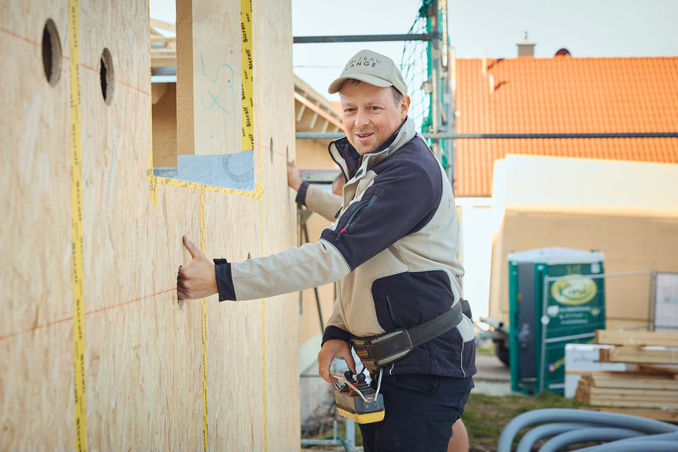 Geschäftsführer Philipp Lange hält mit einem weiteren Bauarbeiter im Hintergrund eine Holzwand