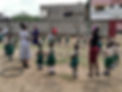 School children in Mombasa, Kenya dancing outside in circle