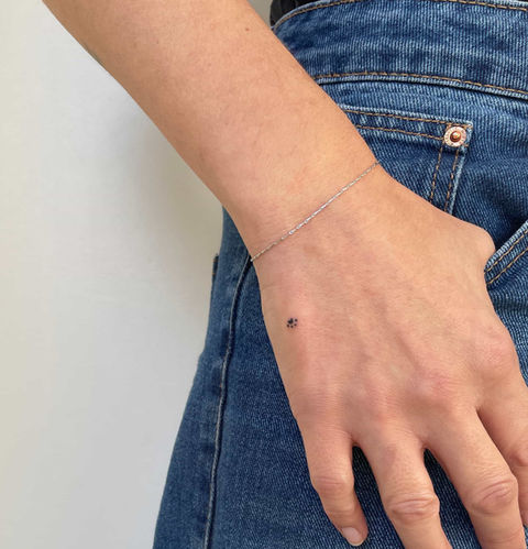 Hand wearing a thin bracelet and minimal tattoo on hand