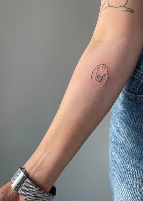 Forearm with small outline tattoo of a head
