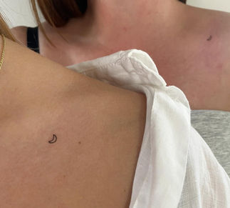 Small crescent moon tattoo on shoulder