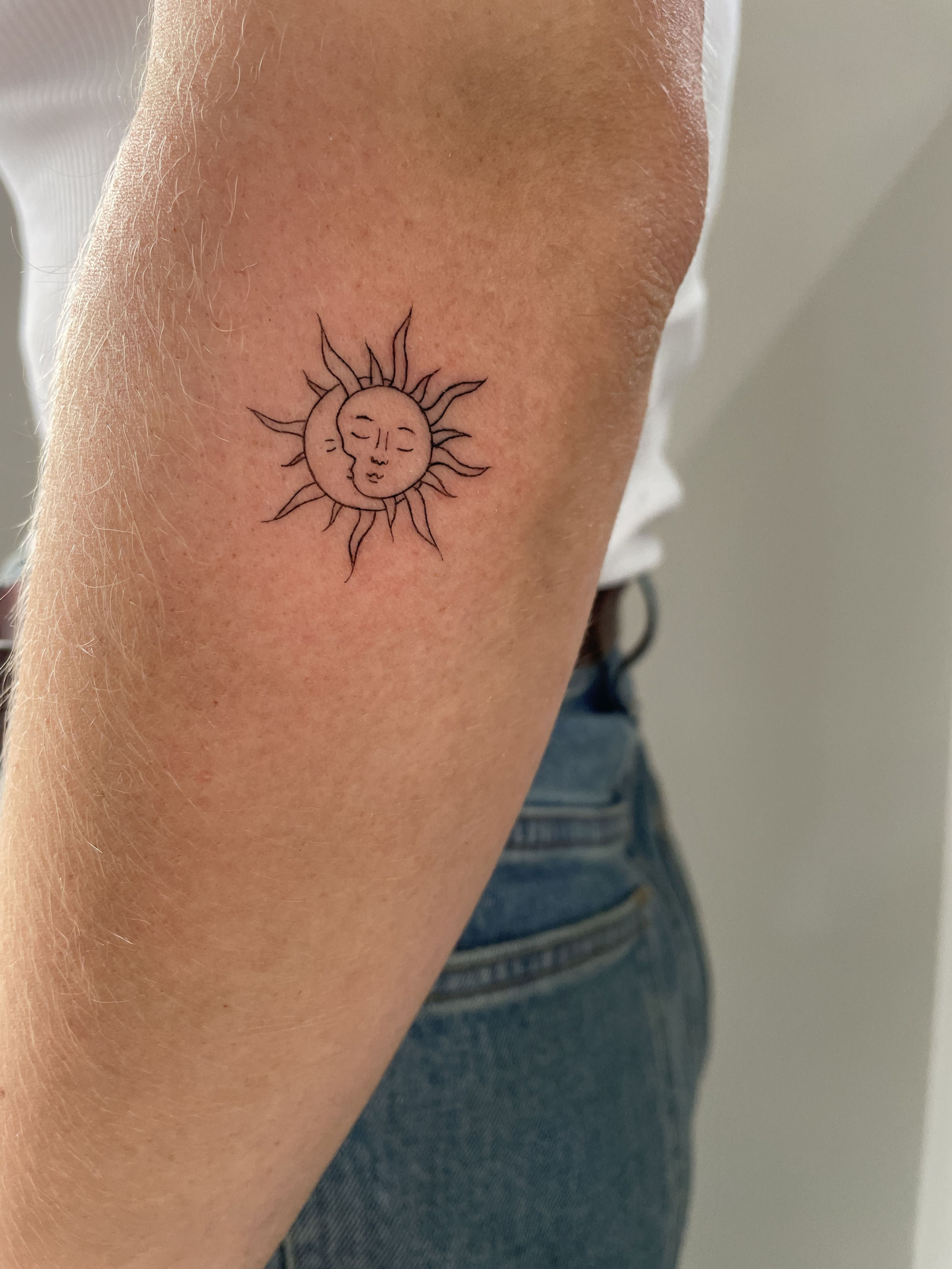Small circular letter tattoo on female shoulder