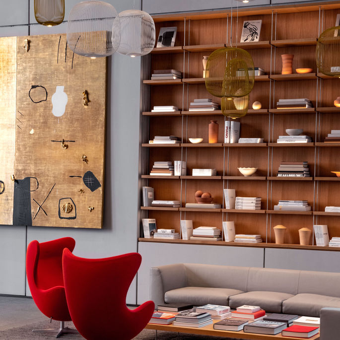 High ceilings and large cement columns provide a beautiful contrast to the modern finishes and furniture that fill the lobby of this residential building.The bright red chairs and built in book shelf add a contemporary feel to this space.