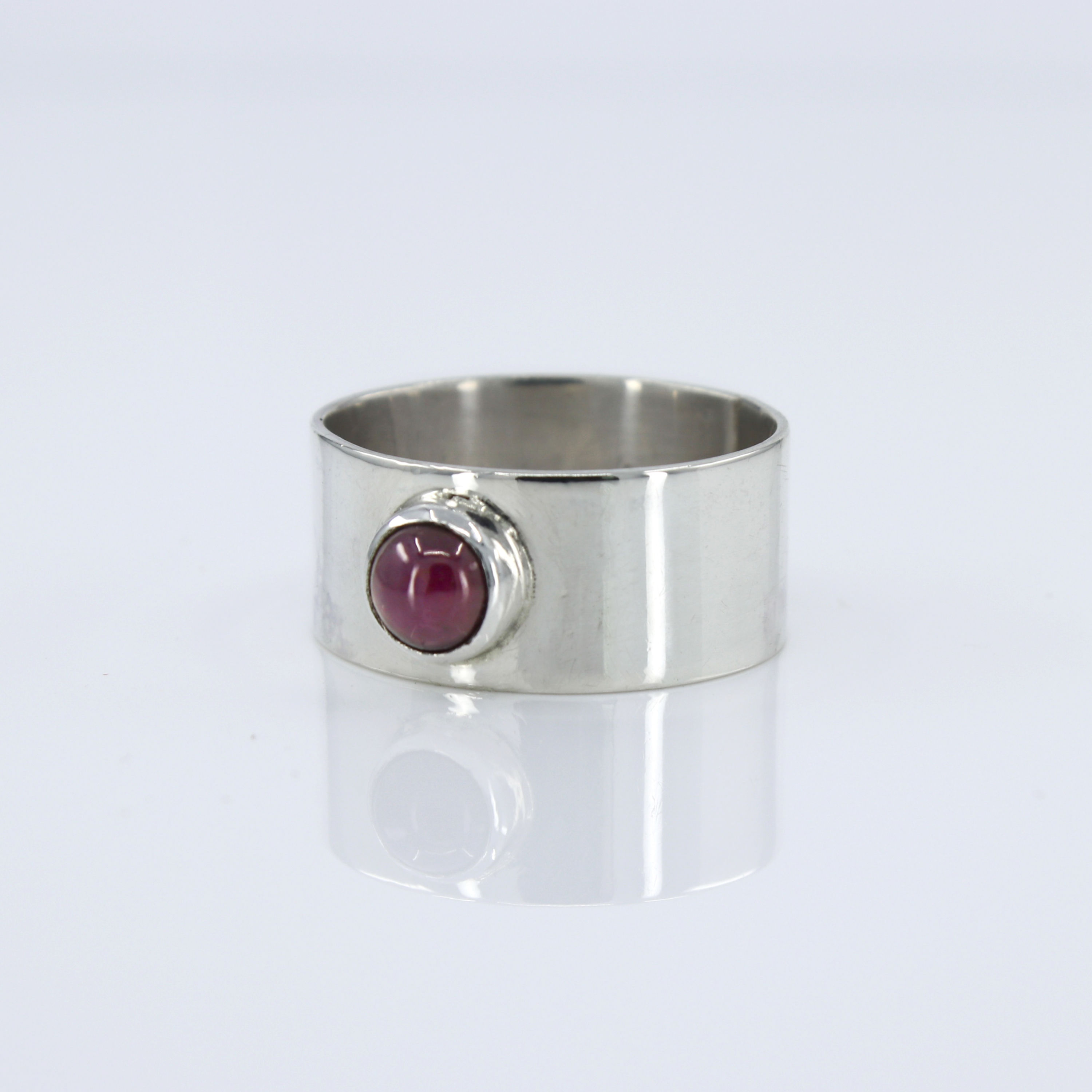 Sterling silver 1/2" wide band accented with a ruby cabochon size 8.5