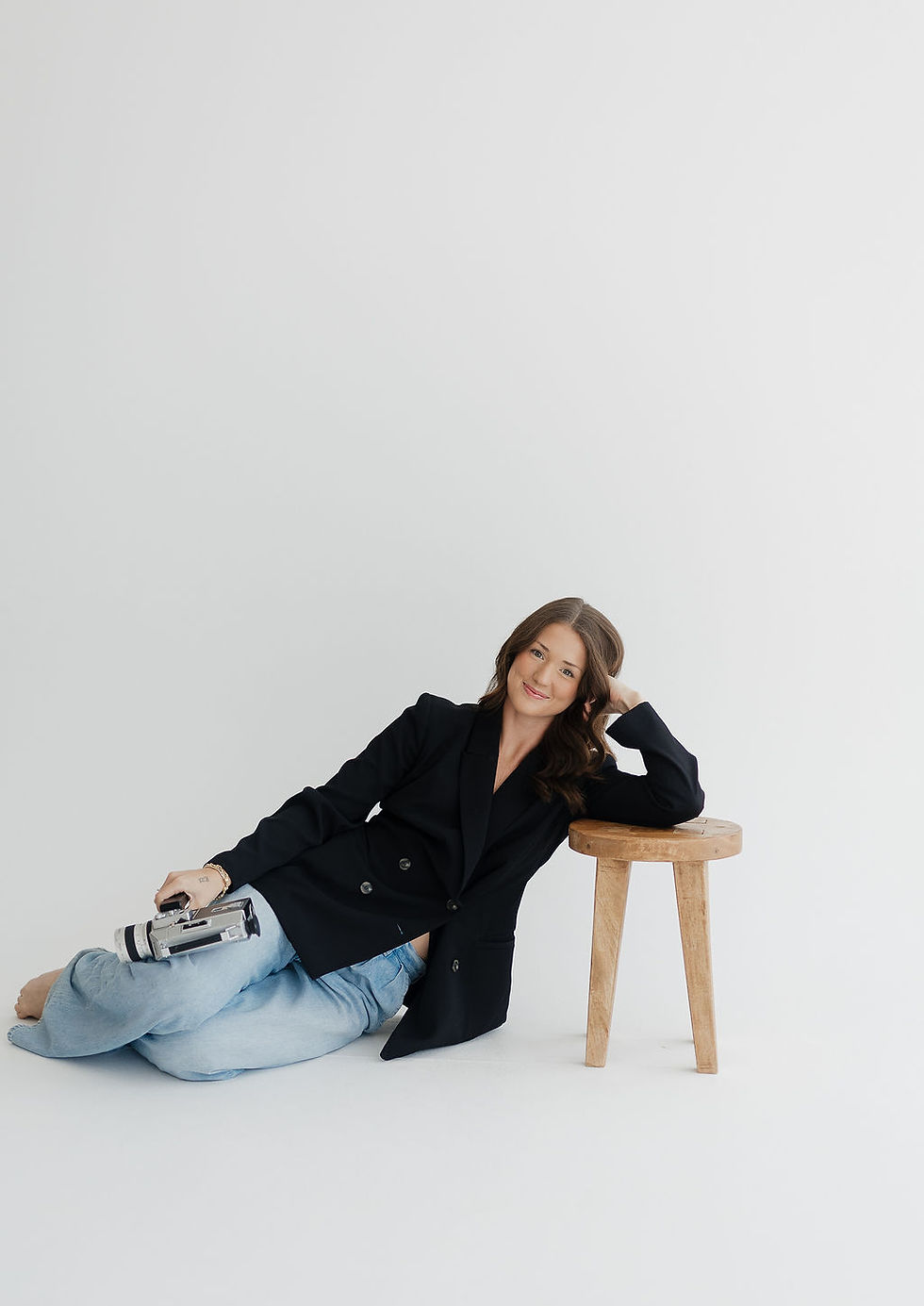 Grace sitting on the floor in a studio, holding a vintage camera