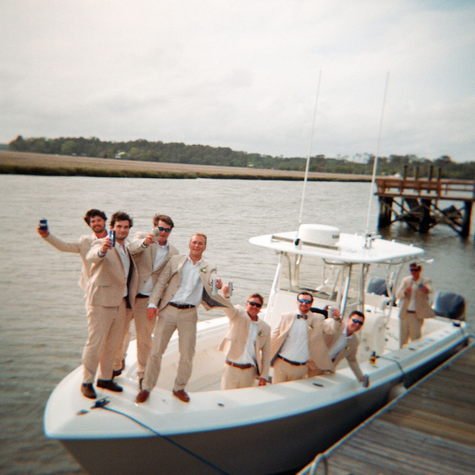 Groomsmen posing together on a boat at the dock