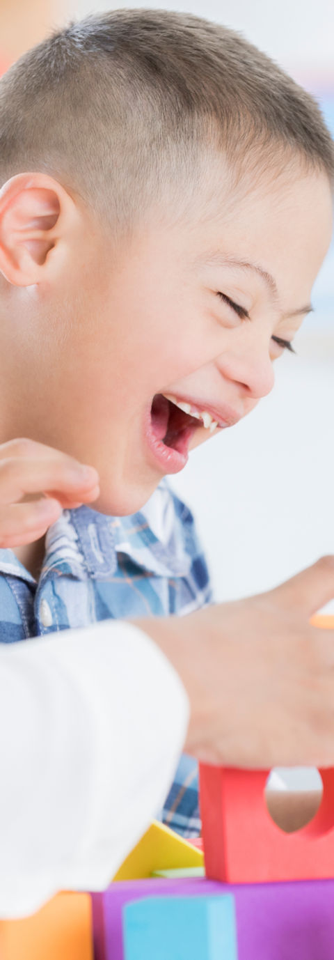 A young boy with disability participating in therapy with brightly coloured blocks.
