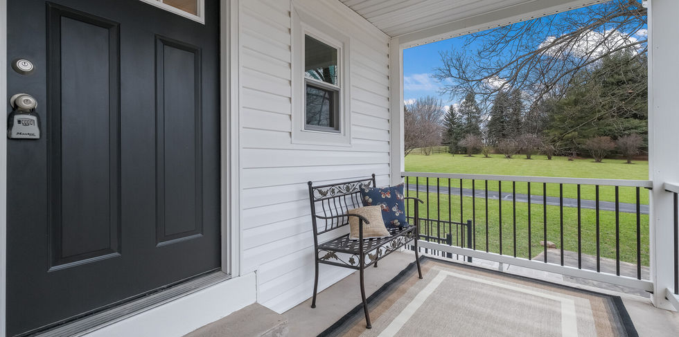 Front porch of a home with a black front door and a bench