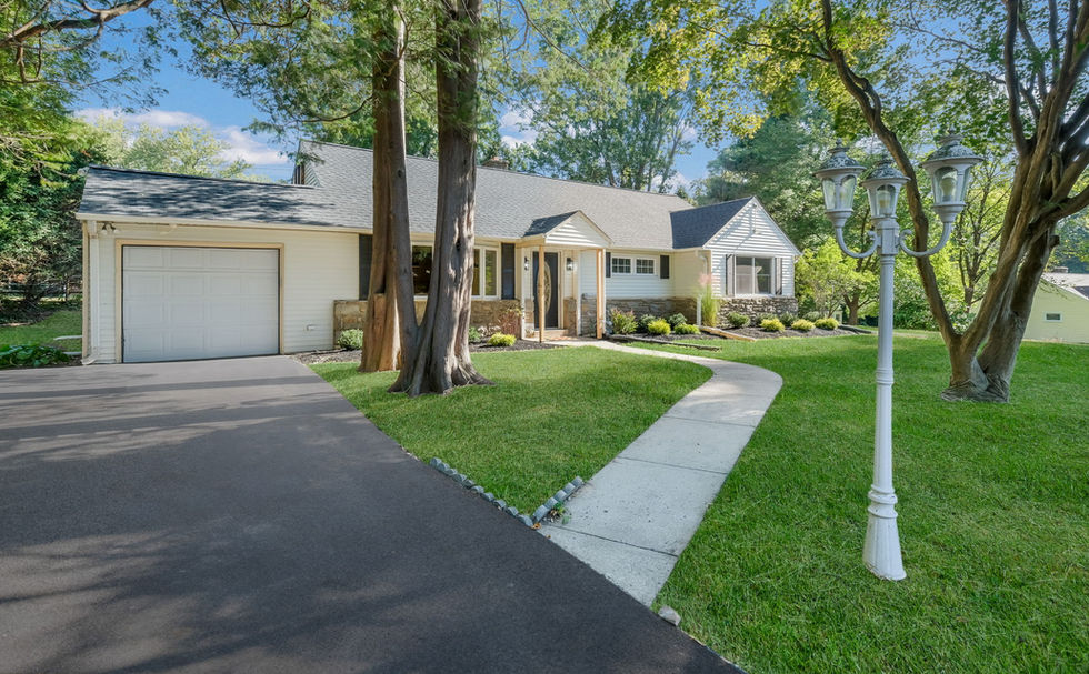 Refreshed front exterior of a home with large driveway and a cement pathway leading towards the front door.