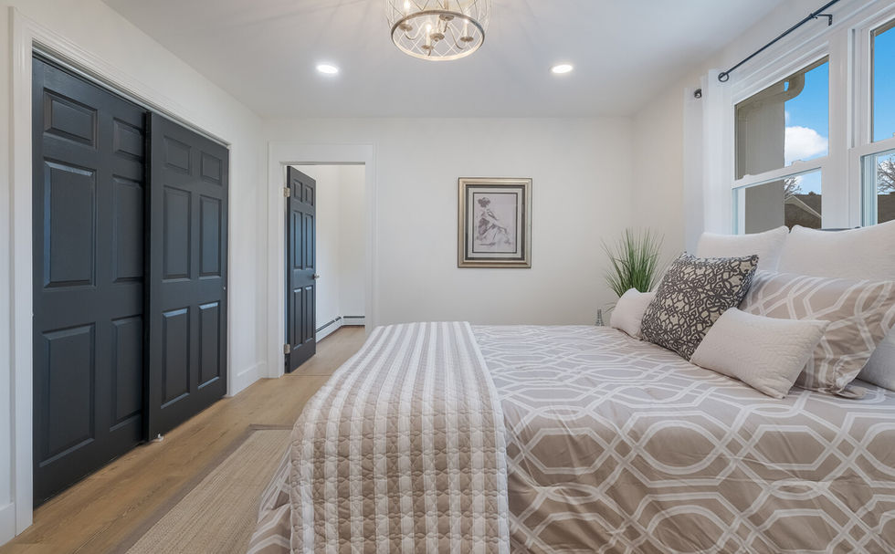 Large bedroom with a king sized bed and a large closet with dark gray sliding doors