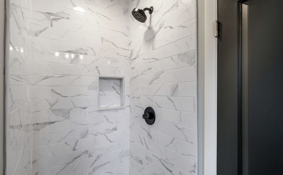 Shower with black fixtures and white marble tiles on each wall
