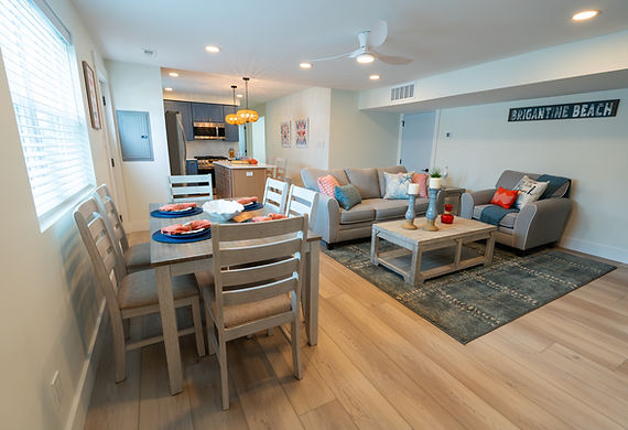 Coastal themed interior with furnished living room area, dining area and modern kitchen