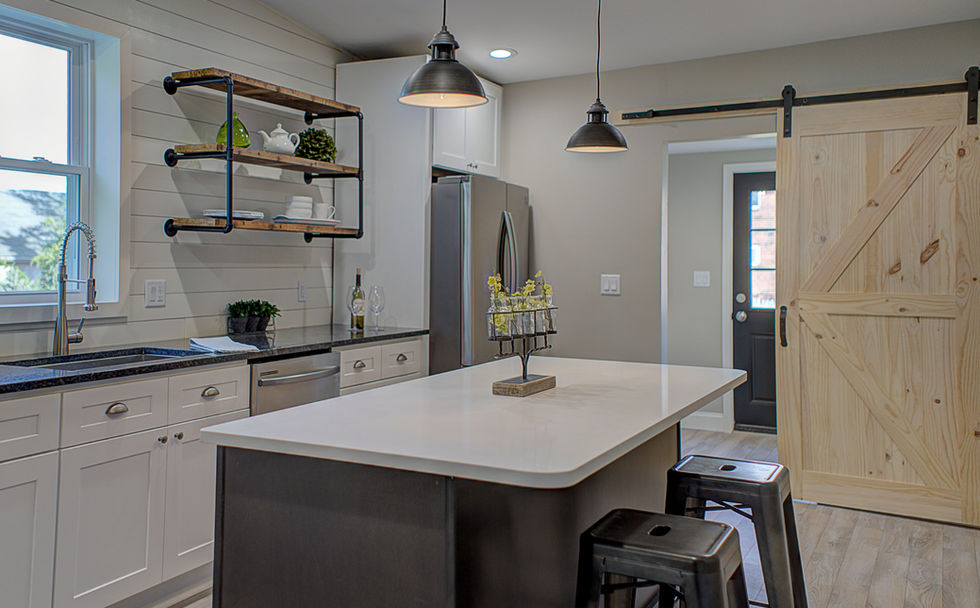 Modern, black and white themed kitchen with wooden accents and a white paneled accent wall behind the cabinets
